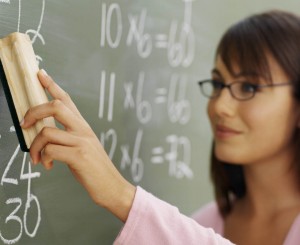 Teacher cleaning chalkboard with duster --- Image by © Royalty-Free/Corbis